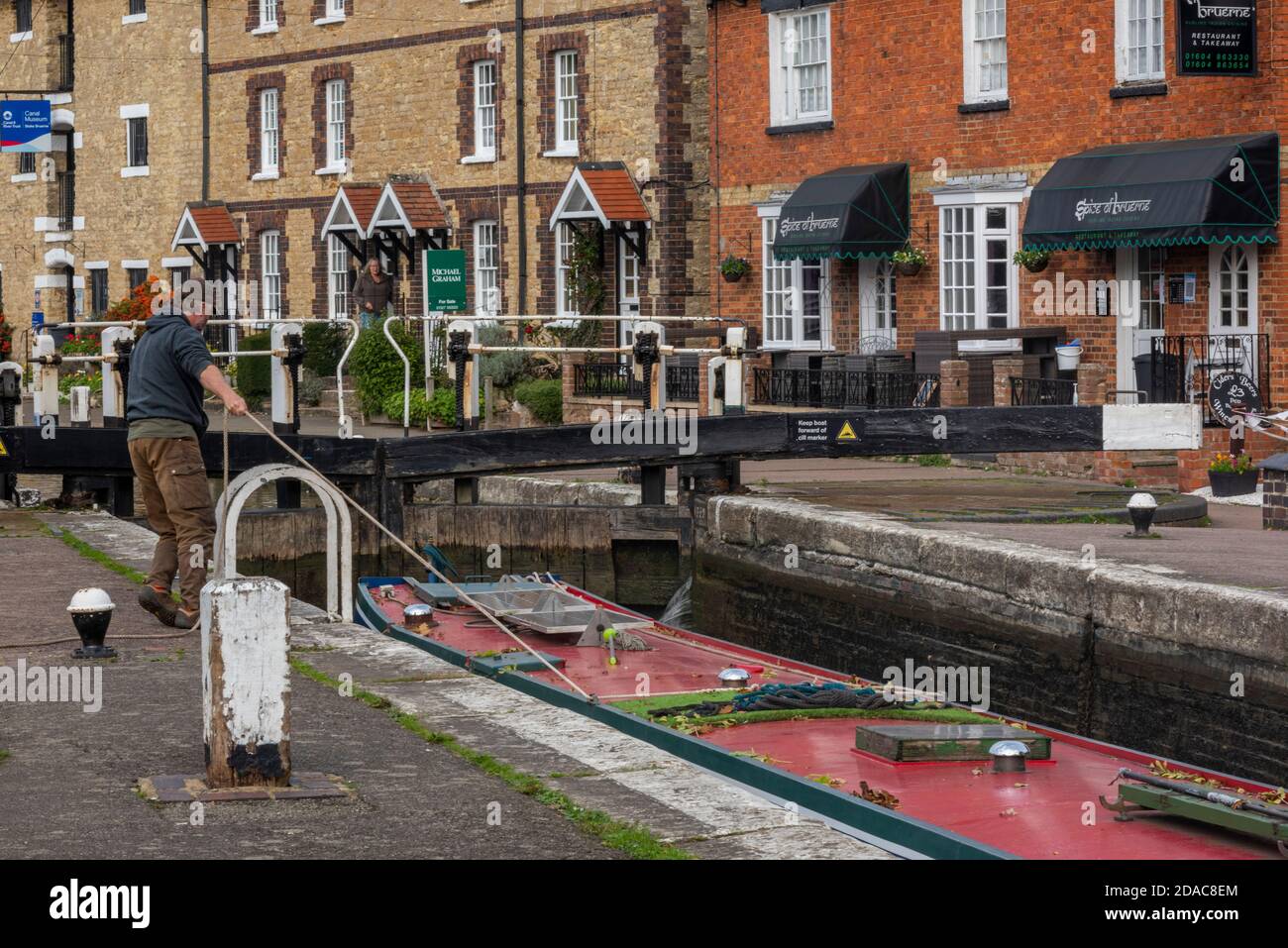 uomo che si legano su barca stretta che entra in una serratura sul canale di grand union a stoke bruerne nel northamptonshire, regno unito Foto Stock