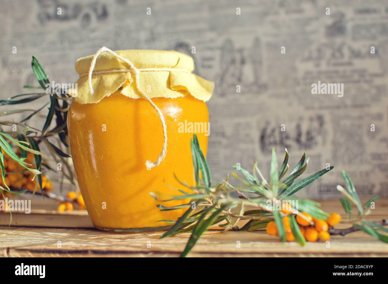 Vasetto di vetro con sciroppo di fibbone di mare sul legno rustico tabella Foto Stock