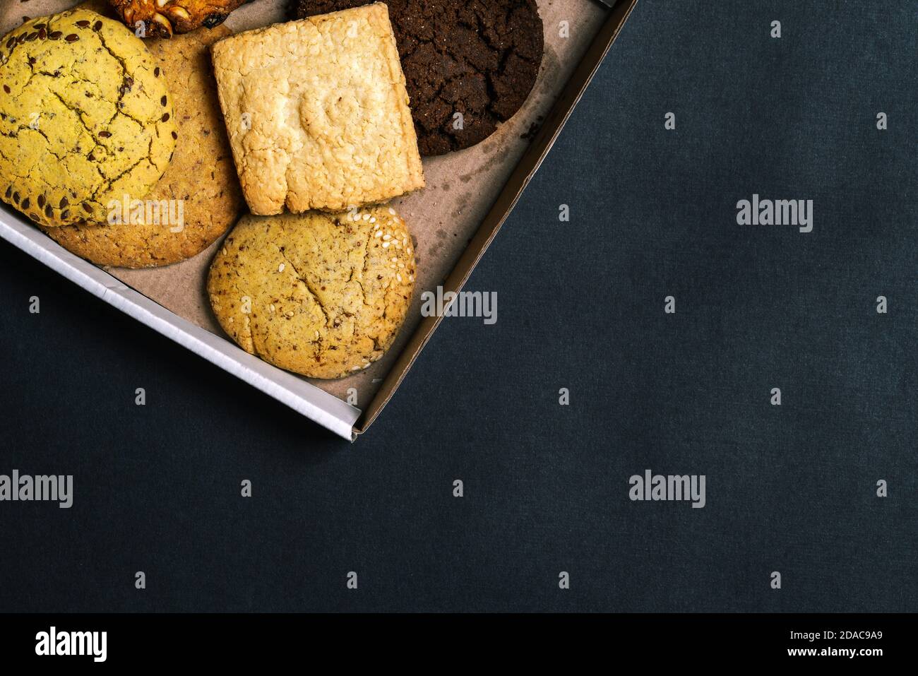 In una scatola di cartone sono presenti vari tipi di dolci. Primo piano di torte fatte in casa al forno con spazio per la copia. Confezione regalo con pasticcini. Vista dall'alto, disposizione piatta Foto Stock