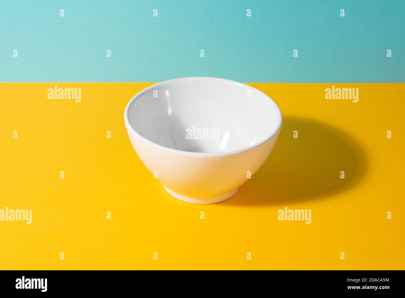 Svuotare il recipiente in ceramica bianco su sfondo giallo e blu Foto Stock
