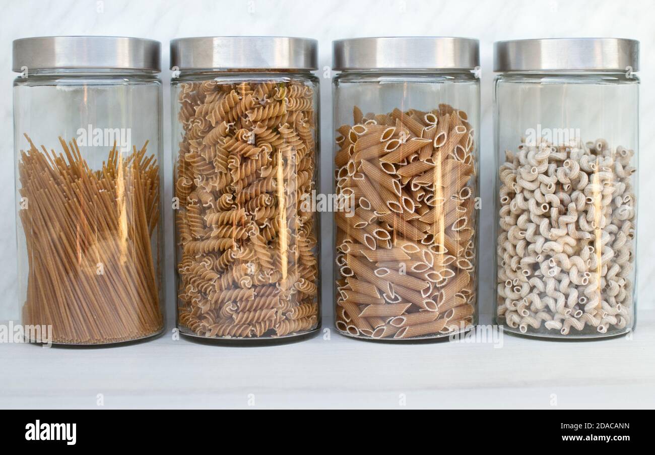 Quattro grandi vasetti di vetro con diverse paste a grani interi in cucina. Foto Stock