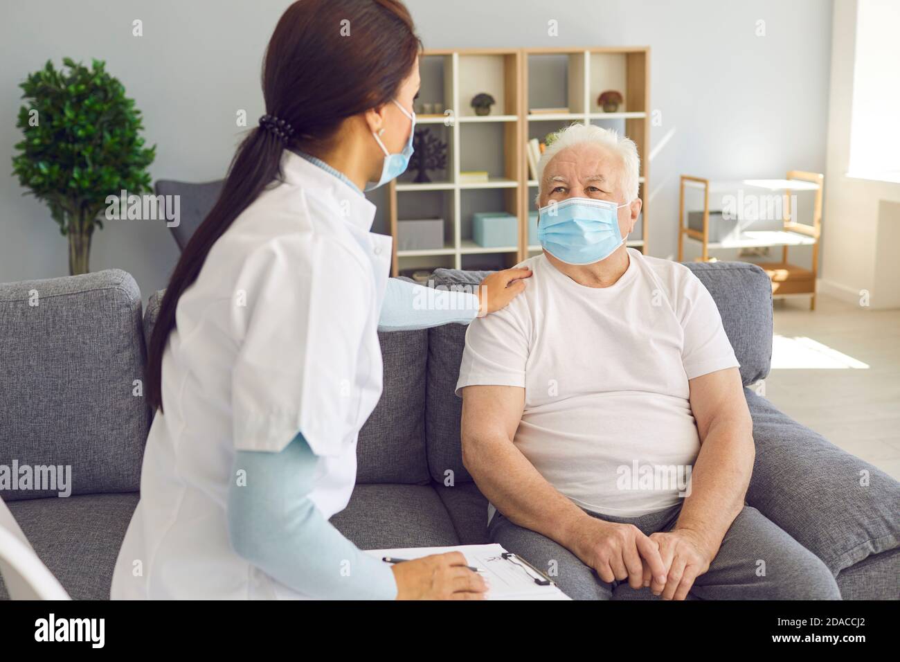 Amichevole medico di supporto che visita pazienti anziani di sesso maschile durante la pandemia di coronavirus. Foto Stock
