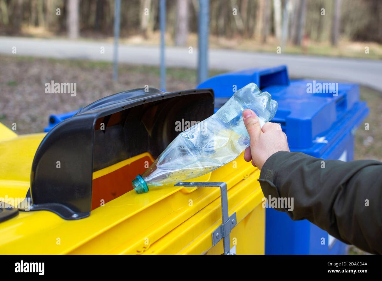 Erson (solo mano nella foto) mette PET (polietilene tereftalato) flacone nel contenitore di riciclaggio Foto Stock