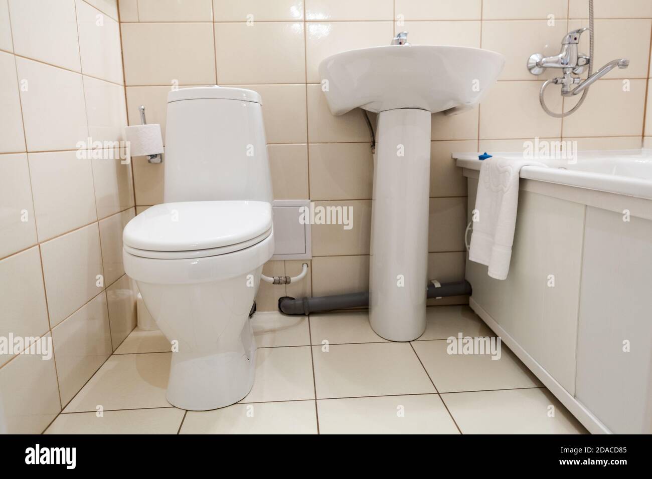 Interno di semplice mezzo bagno con wc, lavabo e vasca con doccia, un  sanitari bianco Foto stock - Alamy