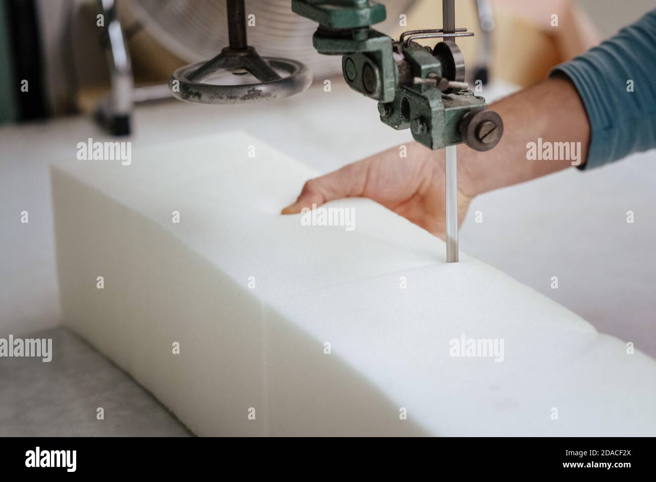 Primo piano di una taglierina per schiuma, tagliando attraverso una schiuma per tappezzeria Foto Stock