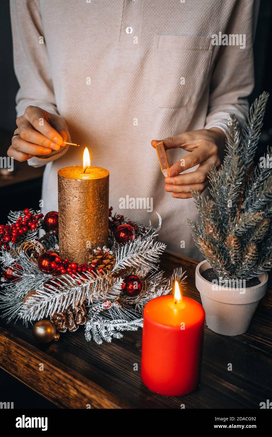 Candele di illuminazione a mano femminile su tavolo decorato a Natale.  Candela bruciante anno nuovo, tempo di avvento, luci calde, decorazioni  invernali ornamenti su vecchio r Foto stock - Alamy