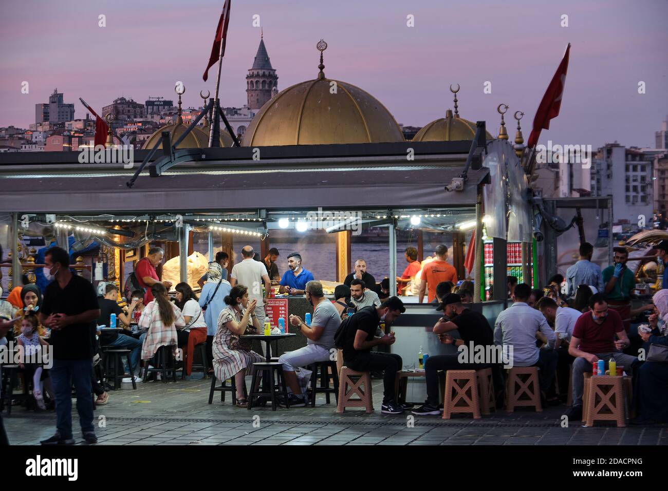 La sera, a Istanbul, Turchia, si mangia in un ristorante barca Balik Ekmek ormeggiato in Piazza Eminonu Foto Stock