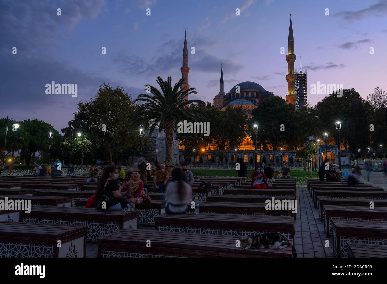 Gente locale seduto su panchine fuori della Moschea Blu al tramonto, Istanbul, Turchia Foto Stock