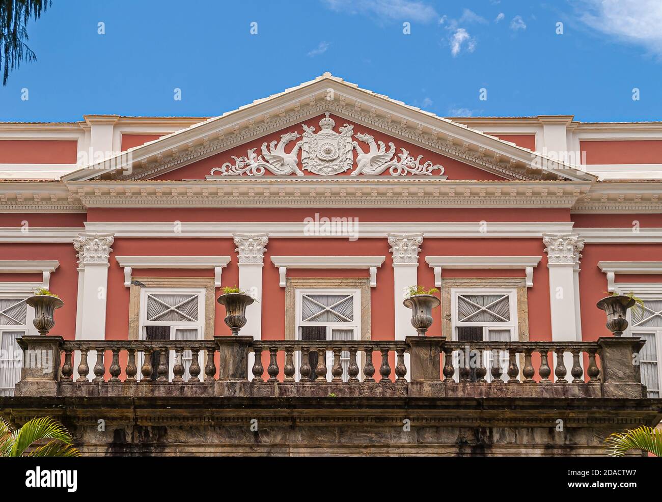 Petropolis, Brasile - 23 dicembre 2008: Emblema imperiale in affresco bianco sulla facciata rosa con cornici bianche di finestre sul Museu Imperiale, ex palazzo. Foto Stock