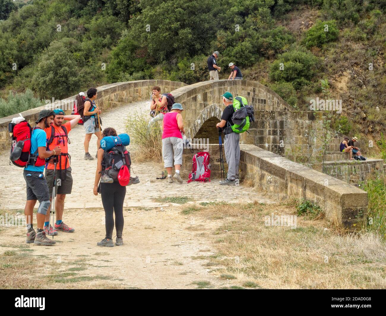 I pellegrini hanno una breve pausa al ponte romano sul fiume Caudiel - Lorca, Navarra, Spagna Foto Stock