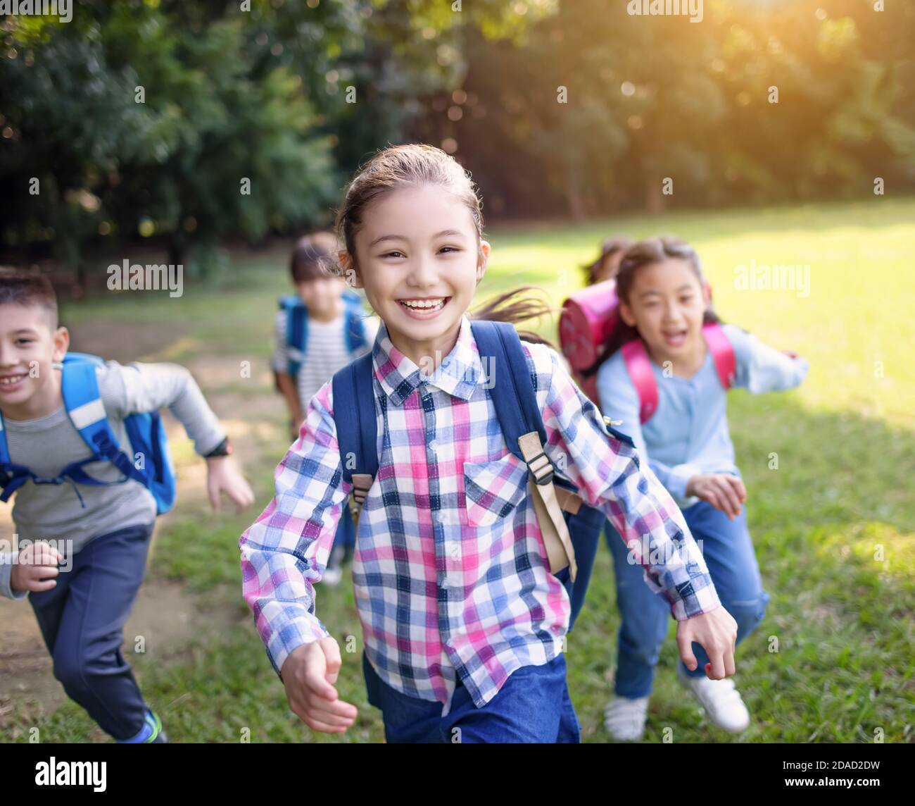 Gruppo di bambini delle scuole elementari che corrono sull'erba Foto Stock