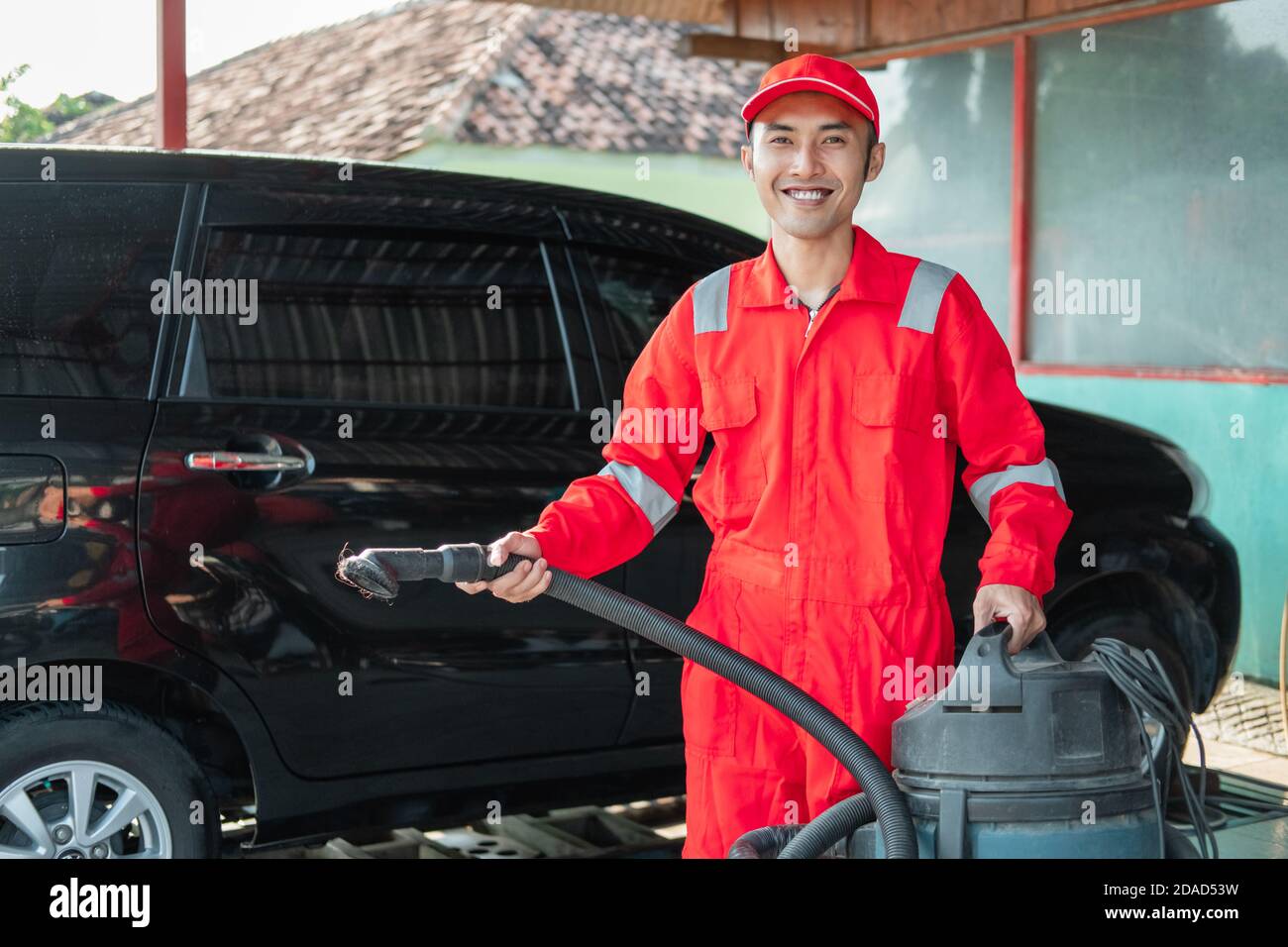 aspirapolvere da auto maschile con aspirapolvere da trasporto uniforme  rosso in salone auto Foto stock - Alamy