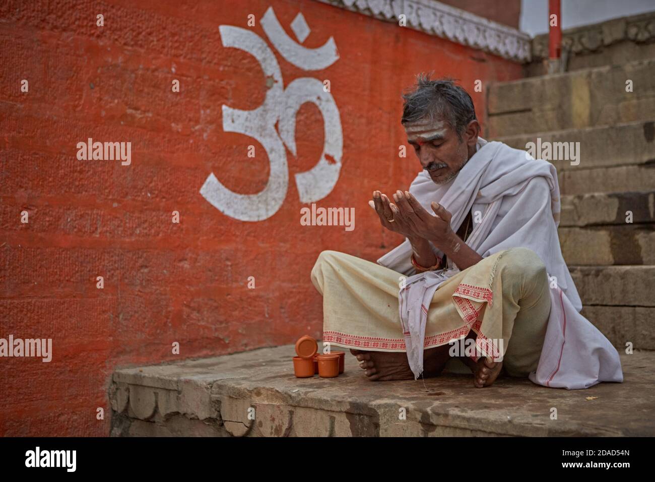 Varanasi, India, novembre 2015. Un uomo prega in un ghat sul fiume Gange. Foto Stock