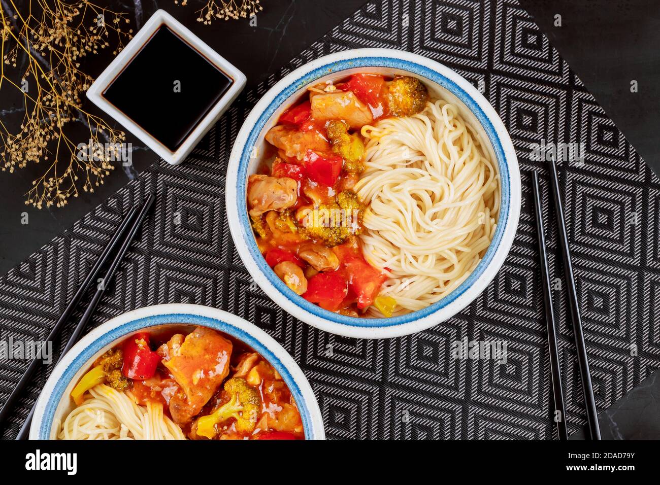 Teriyaki di pollo con peperoni, broccoli e tagliatelle in ciotola con bastoncini. Vista dall'alto. Foto Stock