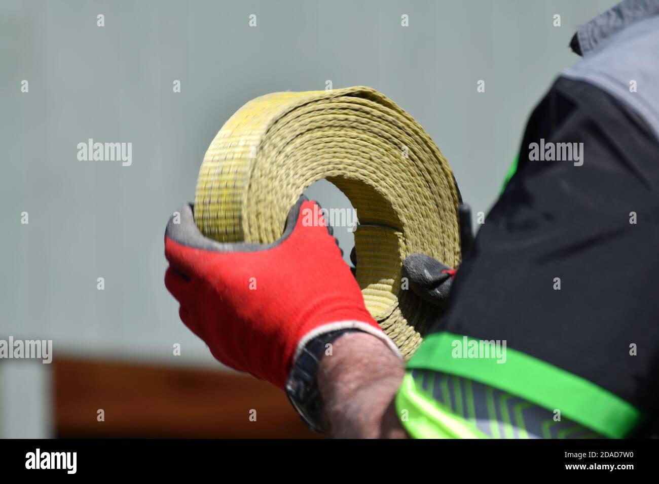 Un operatore di gru arrotola una cinghia di ancoraggio Foto Stock