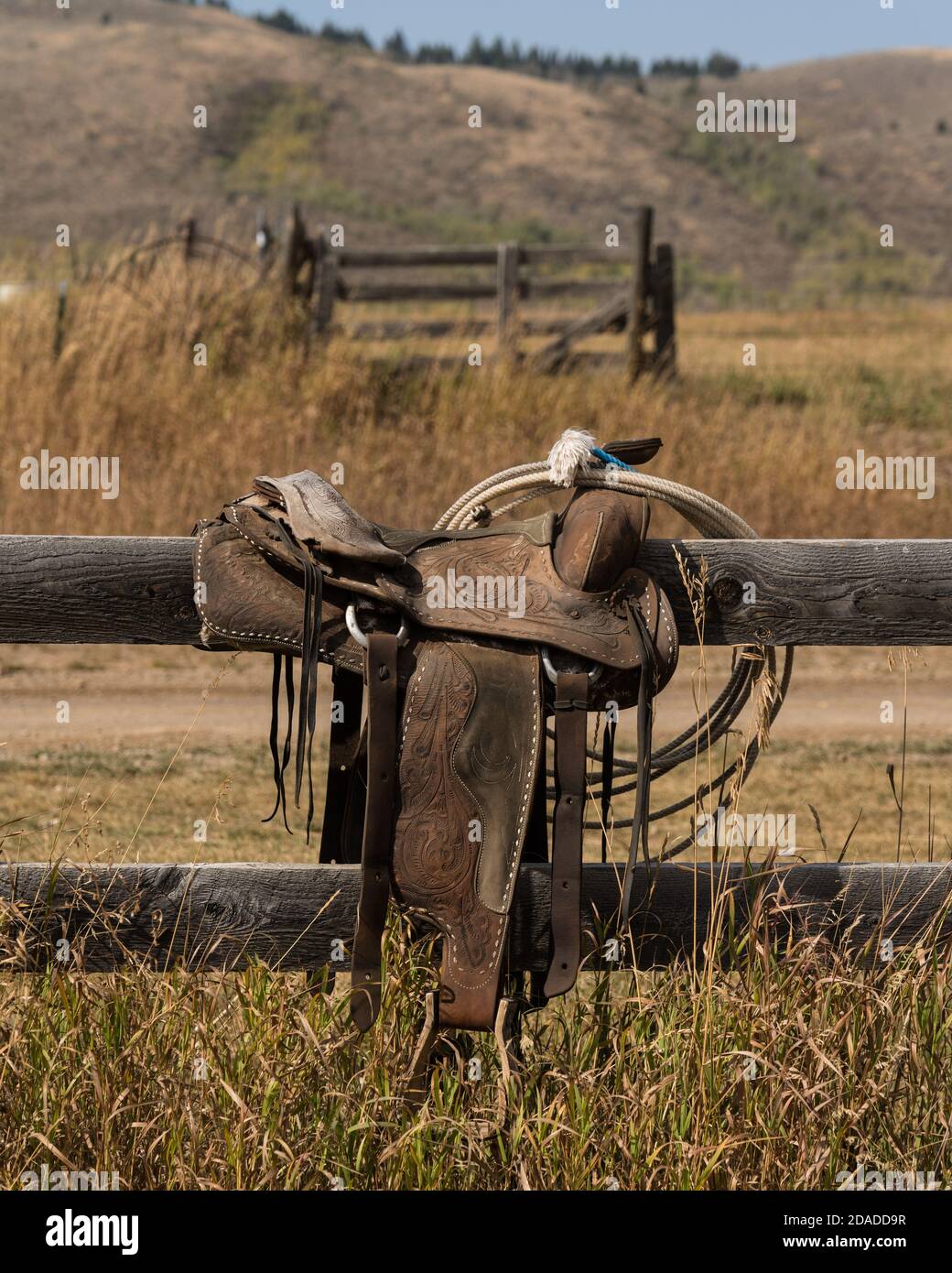 Una vecchia sella di guida occidentale in pelle con utensili su una recinzione ranch in Idaho. Ora parte di un museo privato. Foto Stock
