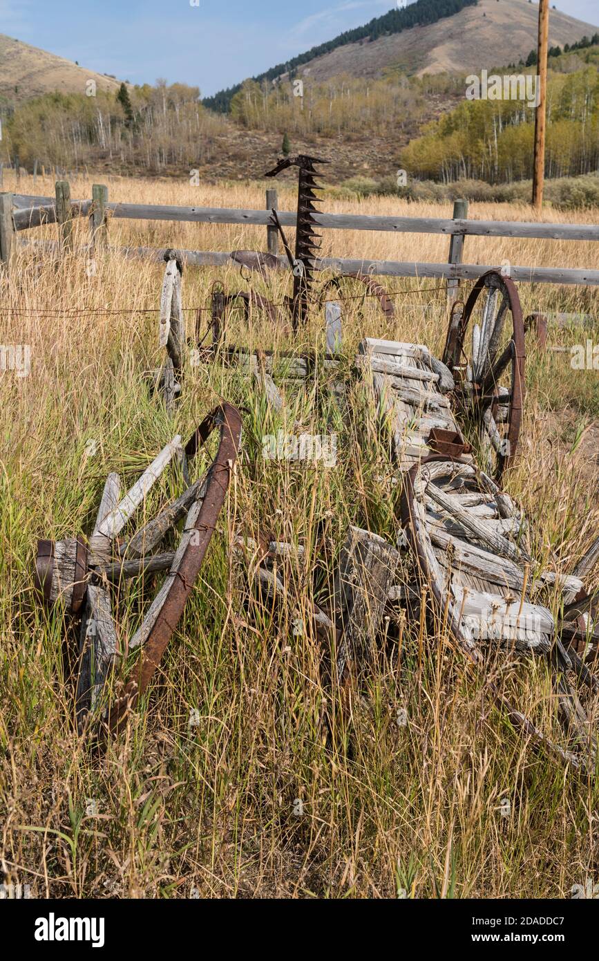 Un vecchio carro pionieristico rotto con ruote a raggi di legno e un falciafieno vintage su un ranch in Idaho. Ora parte di un museo privato. Foto Stock