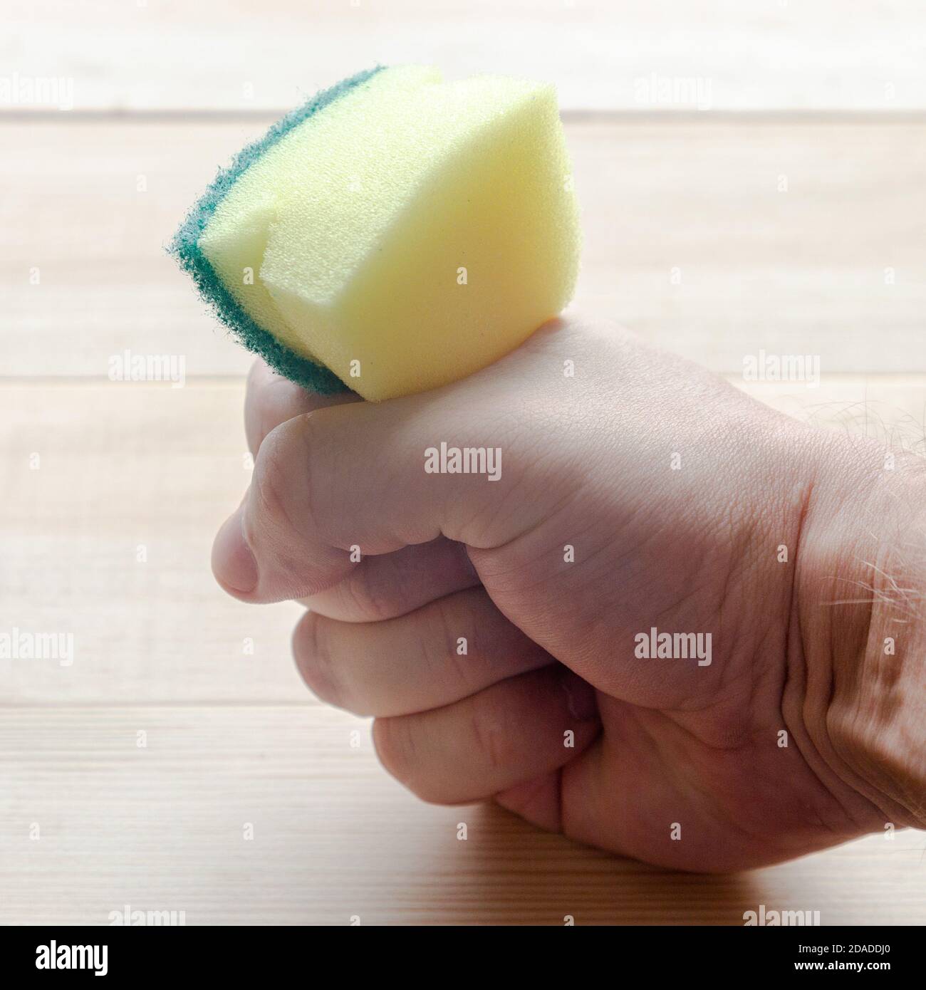 La mano strizza una spugna una spazzola per piatti su un legno tabella Foto  stock - Alamy