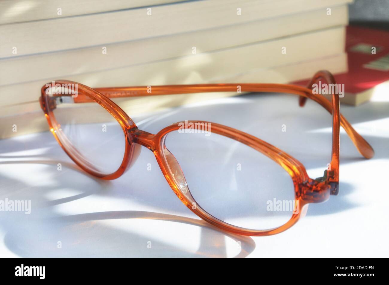 Gli eleganti occhiali si trovano nelle vicinanze dei numerosi libri. Concetto di lettura. Foto Stock