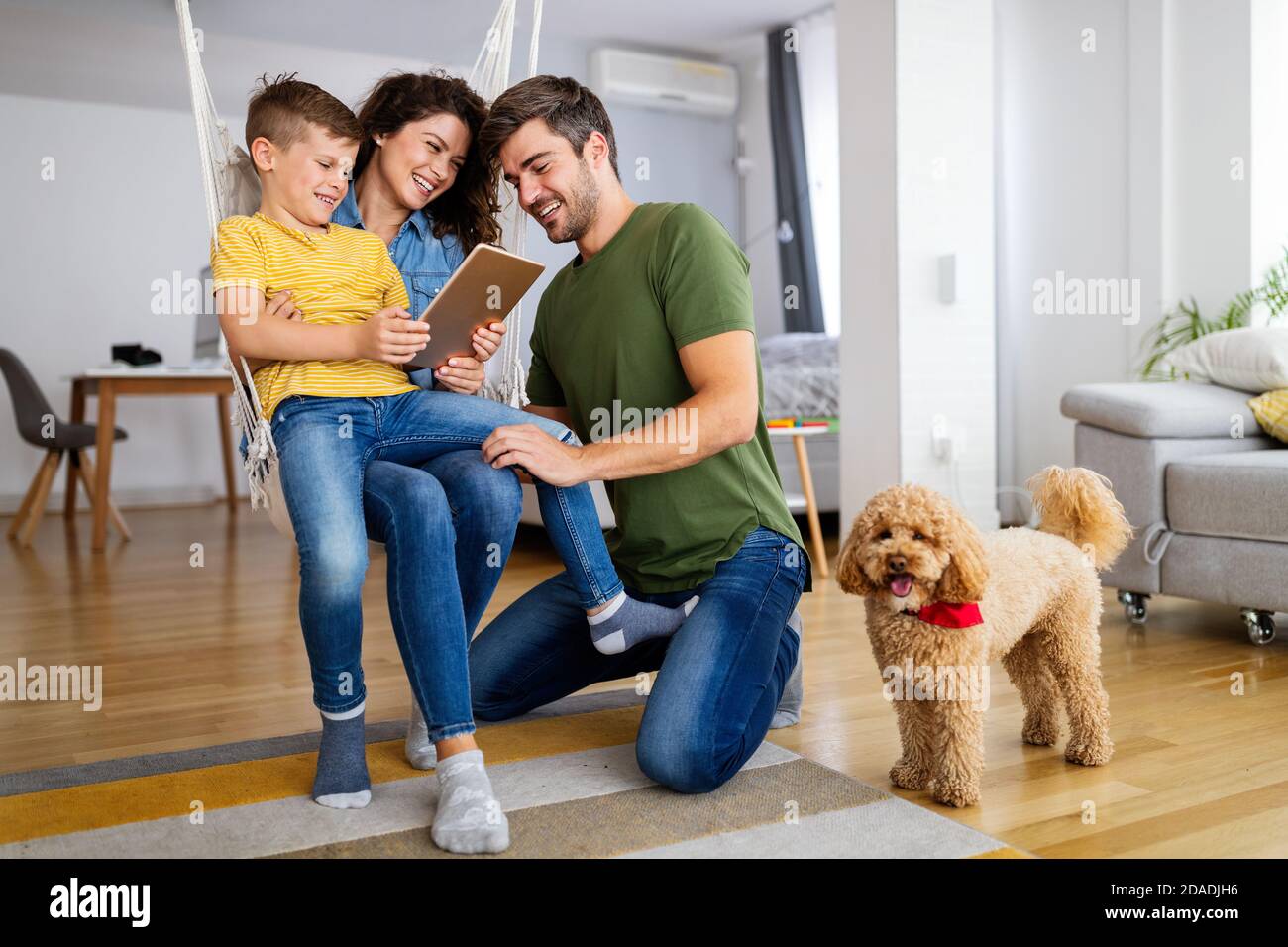 Felice famiglia con i dispositivi moderni e cane divertirsi, giocando a casa Foto Stock