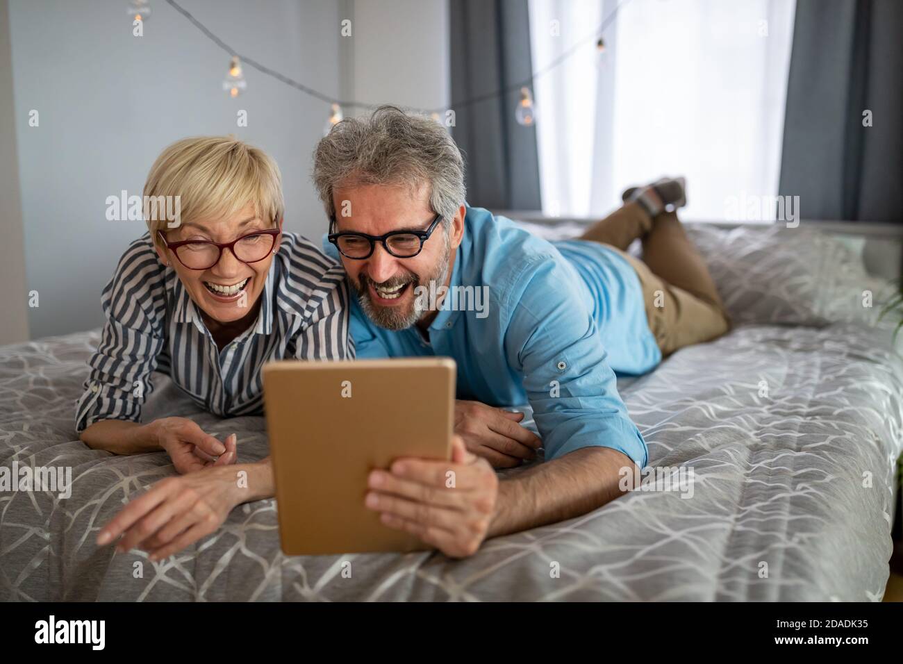 Bella coppia sorridente matura che si diverte mentre si usa tablet a. casa Foto Stock