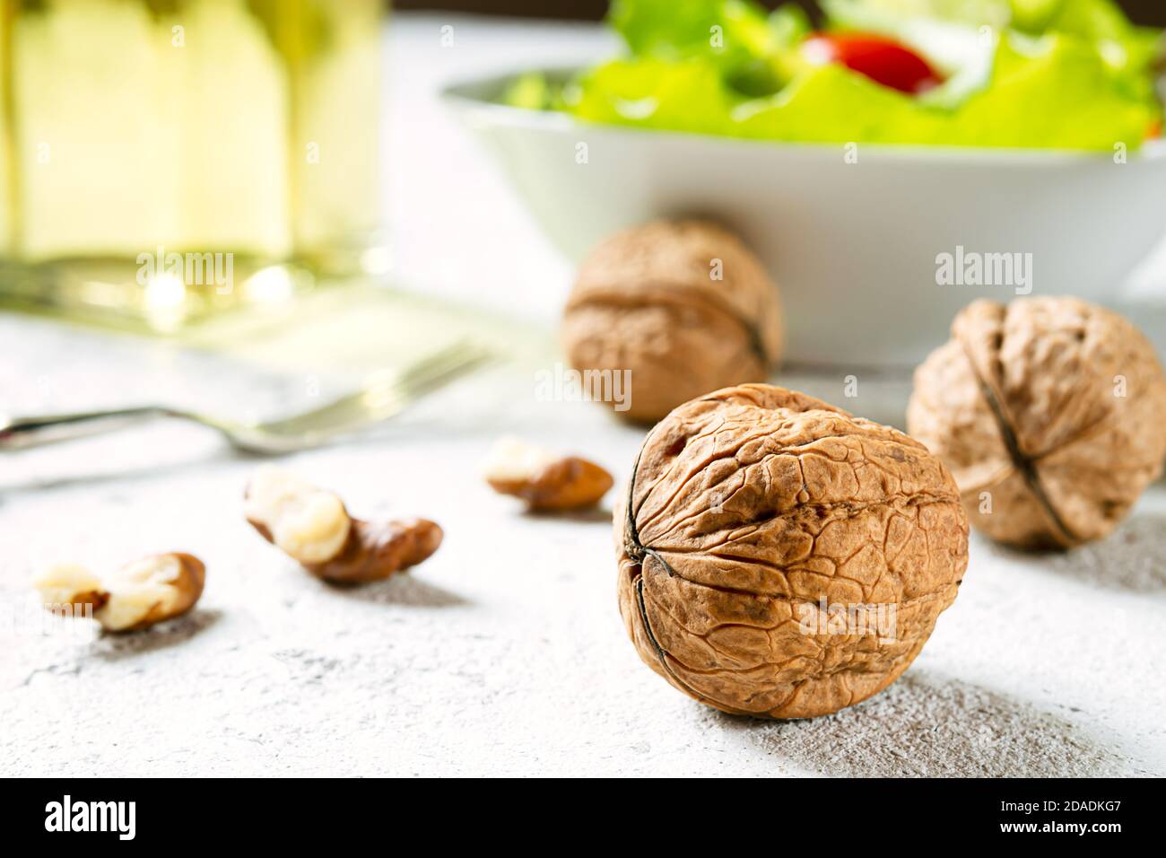 Noci biologiche fresche per olio di noce primo piano come olio d'oliva alternativa su sfondo chiaro e insalata Foto Stock