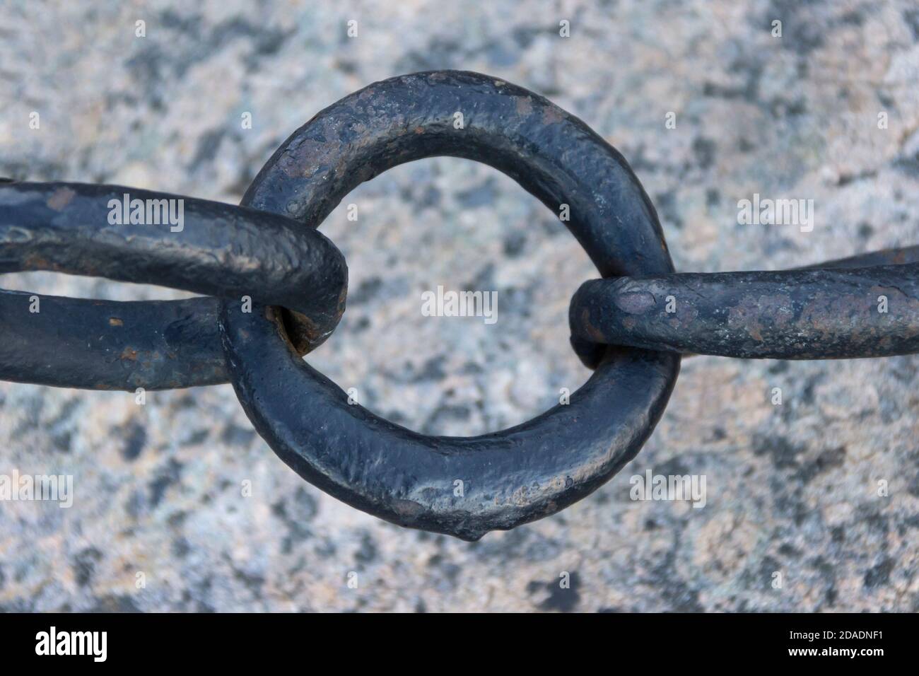 Vecchia catena arrugginita forgiata con vernice che si spellano sullo sfondo delle pietre di pavimentazione. Foto Stock