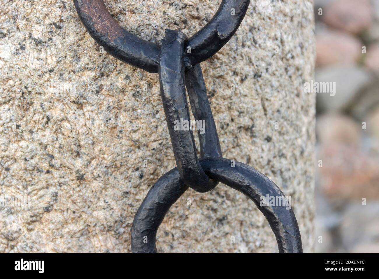 Vecchia catena arrugginita forgiata con vernice che si spellano sullo sfondo delle pietre di pavimentazione. Foto Stock