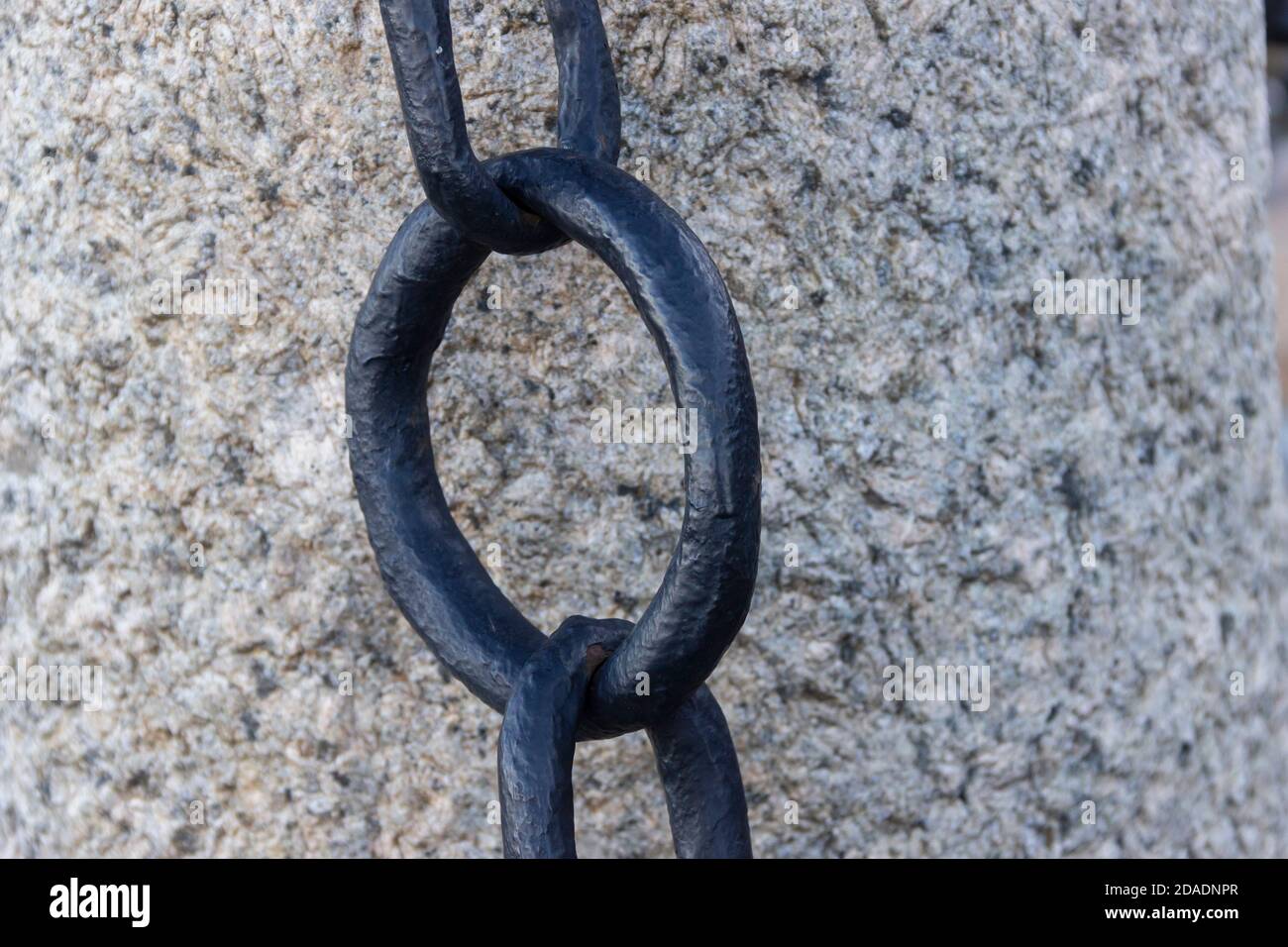 Vecchia catena arrugginita forgiata con vernice che si spellano sullo sfondo delle pietre di pavimentazione. Foto Stock