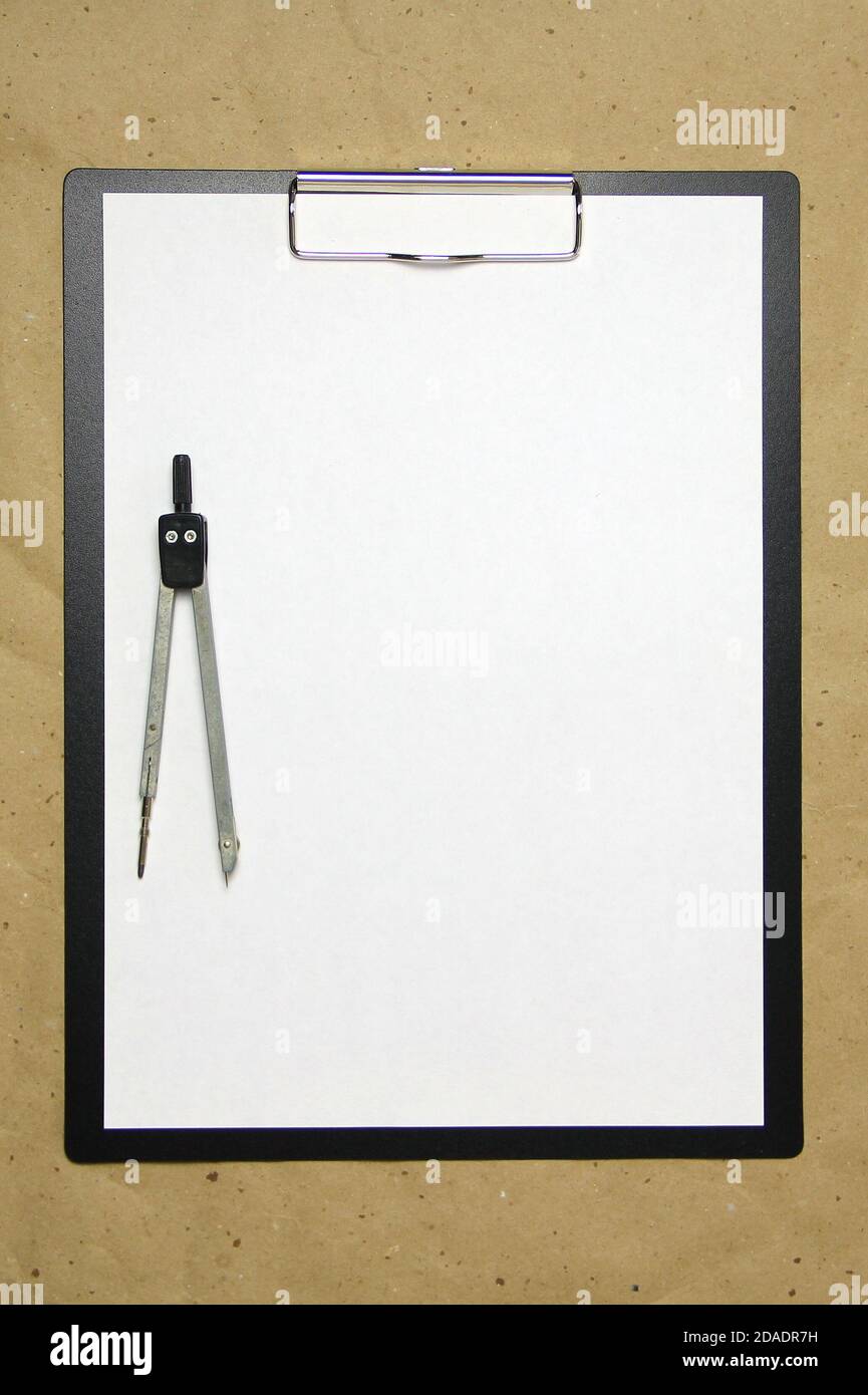 Una tavoletta con un foglio bianco di formato A4 con divisori su una carta da artigianato beige. Concetto di misurazioni, studi e costruzioni accurate. Foto di scorta con spazio vuoto per il testo e il disegno. Foto Stock