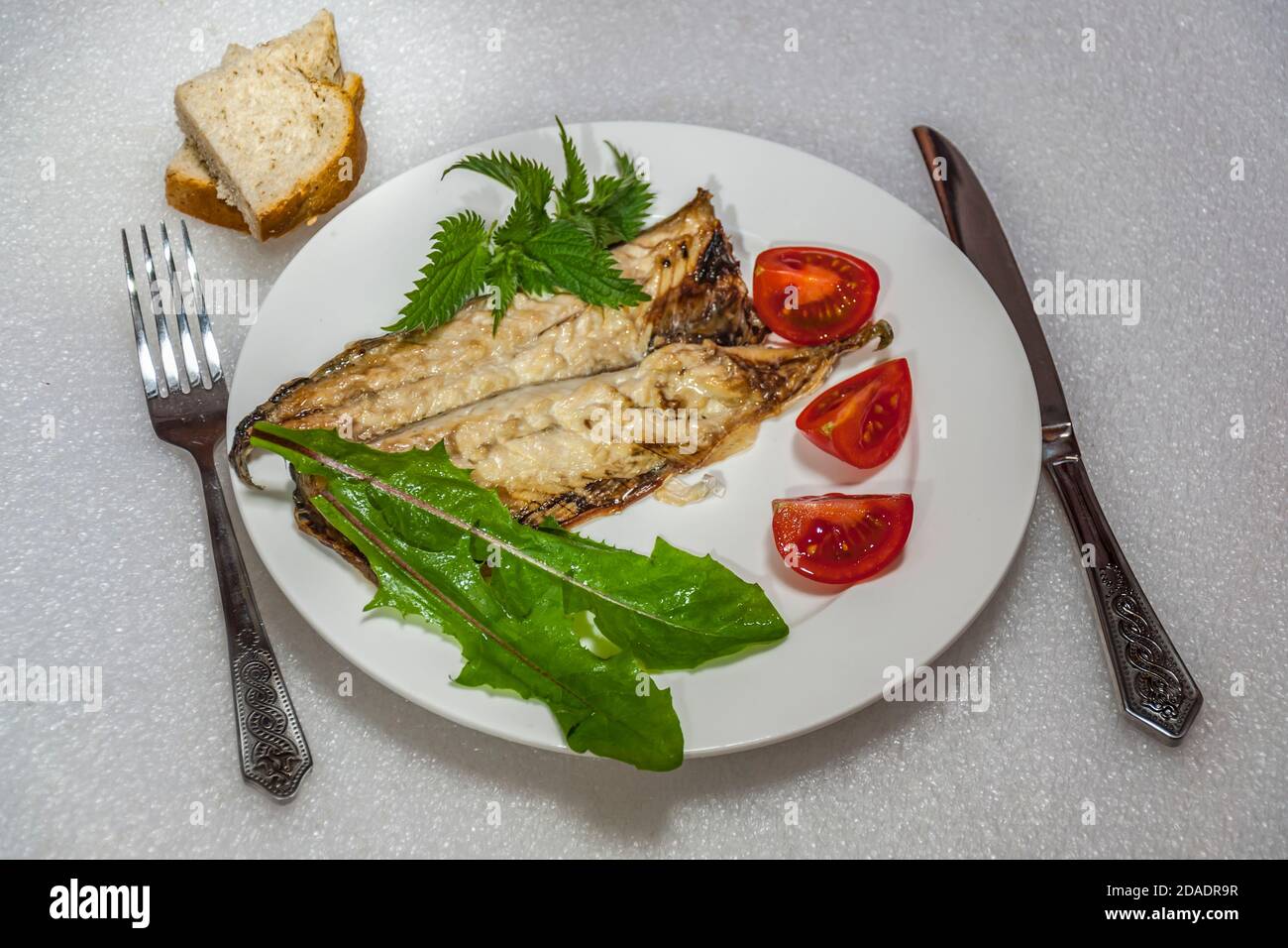 Piatto con ortica di pesce appena sfornata e foglie di dente di leone. Foto Stock