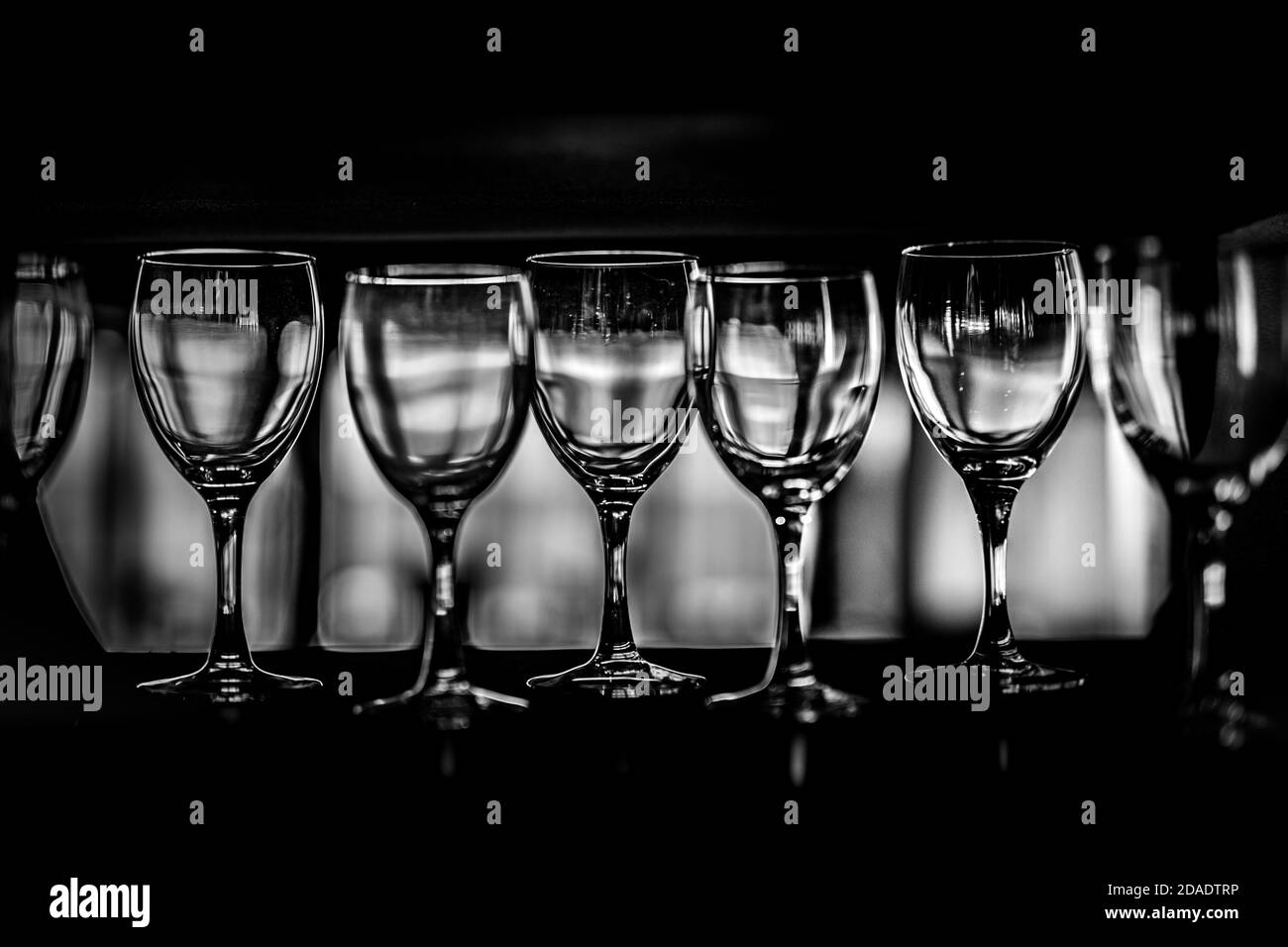 File di bicchieri da vino vuoti sullo scaffale, processo in bianco e nero Foto Stock