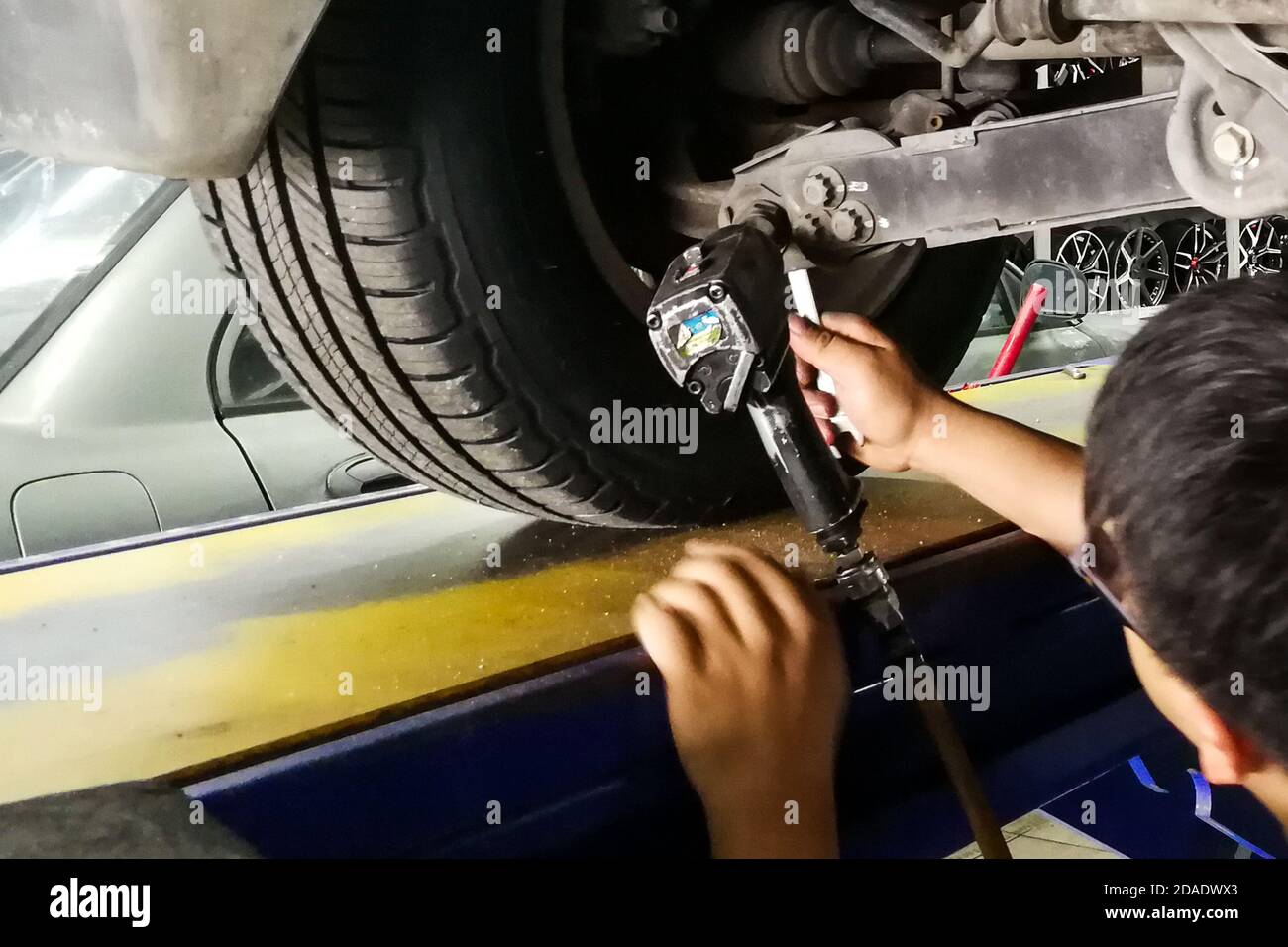Meccanico che regola la campanatura dell'assale in officina durante l'allineamento delle ruote Foto Stock