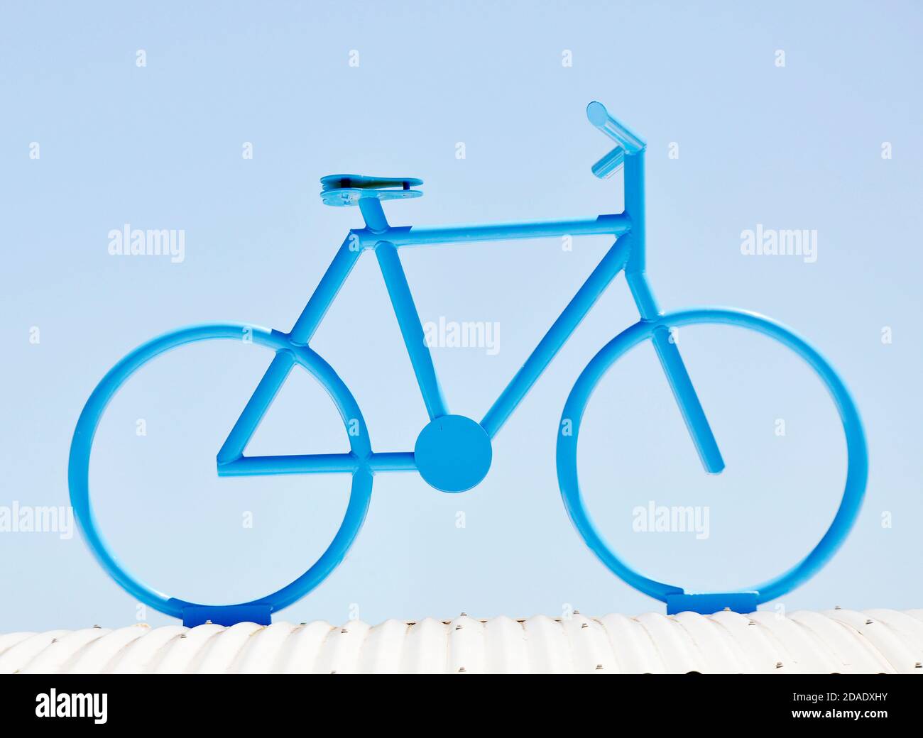 Modello sul tetto di una bicicletta dipinta blu contro un blu cielo Foto Stock