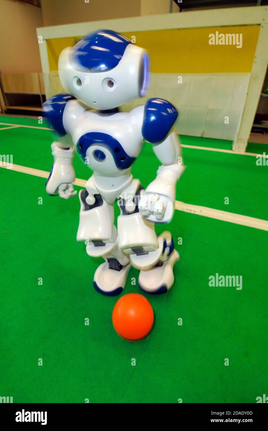 robot umanoide che gioca a calcio o a calcio su un tappetino verde con una  palla arancione Foto stock - Alamy