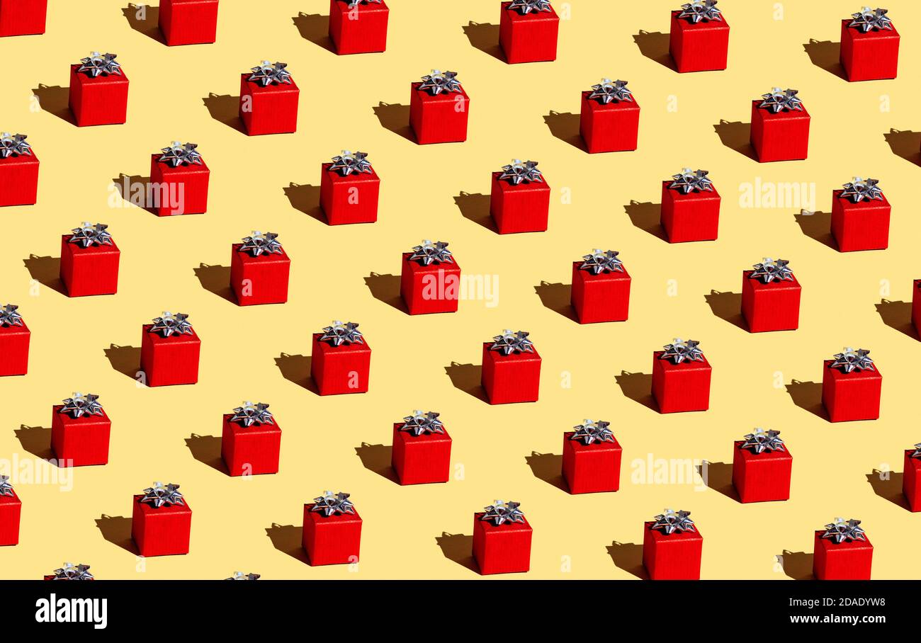 Regalo rosso su sfondo giallo. Ripetizione senza giunture. Avvolgimento. Foto Stock