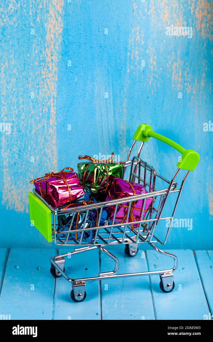 Carrello con regali colorati. Acquisto di regali per la vacanza. Foto Stock