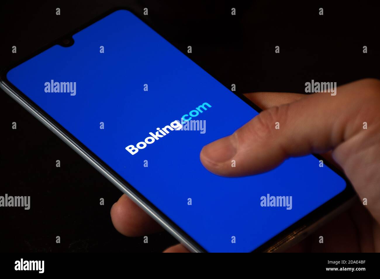 Logo Booking.com visualizzato sullo smartphone con le dita, viaggi e crisi del settore alberghiero a causa della pandemia di Covid o Coronavirus, violazione dei dati Foto Stock