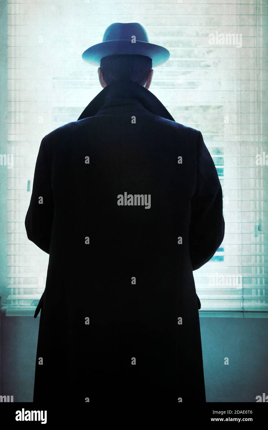 Uomo silhouetted in cappotto e cappello a finestra Foto Stock