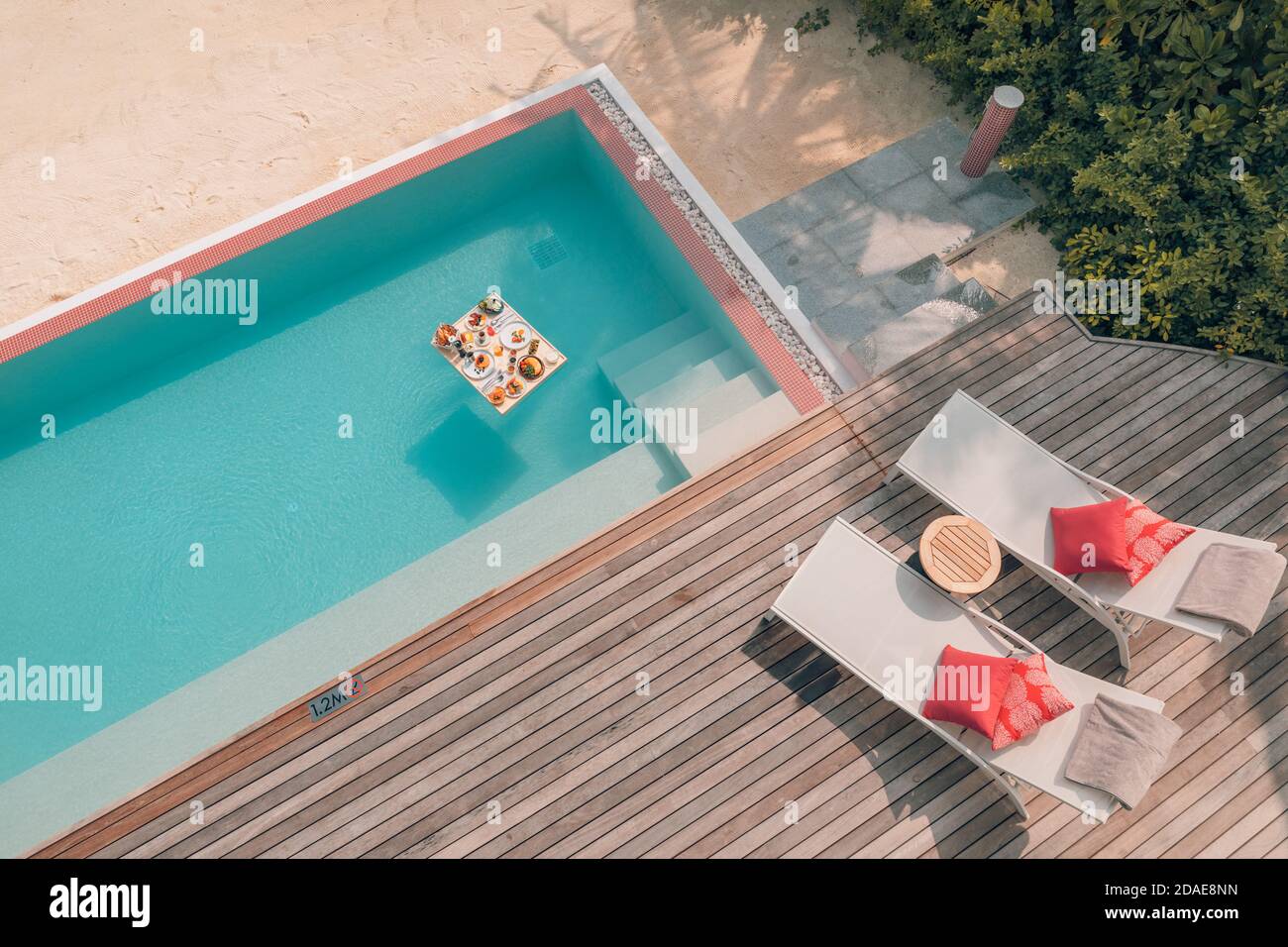 Colazione in piscina, colazione galleggiante in un lussuoso resort tropicale. Tavolo rilassante acqua tranquilla piscina, sana prima colazione di lusso e piatto di frutta Foto Stock
