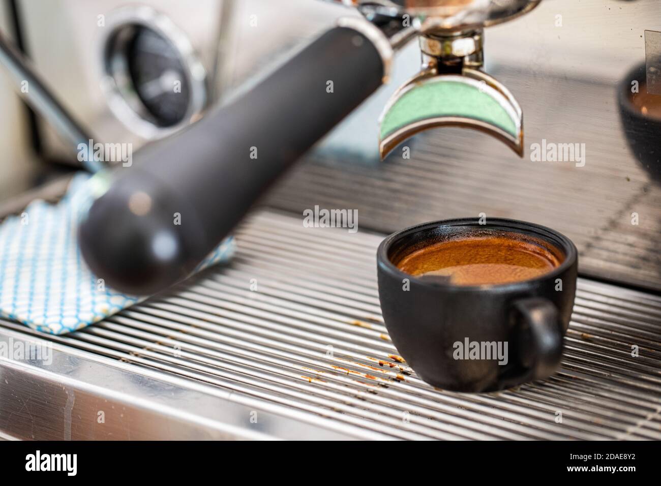 Caffè fresco in tazza di ceramica. Caffè espresso fresco che viene erogato attraverso il portafiltro senza fondo Foto Stock