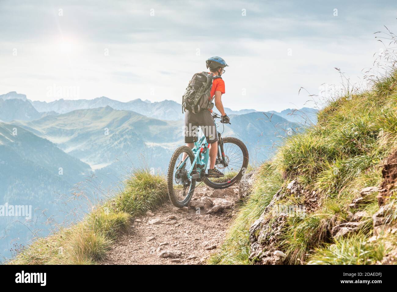 Giovane (22 anni) in bicicletta elettrica lungo un sentiero alpino, Campitello di Fassa, Val di Fassa, Trento, Trentino Alto Adige, Italia Europa Foto Stock