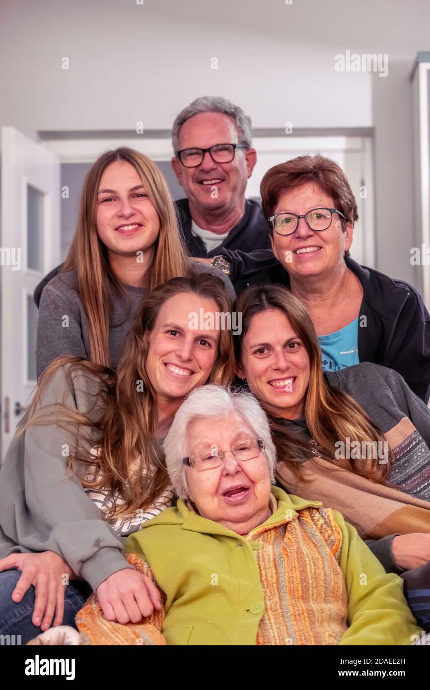 Famiglia di tre figlie, padre, madre e nonna in posa per una foto guardando la macchina fotografica Foto Stock
