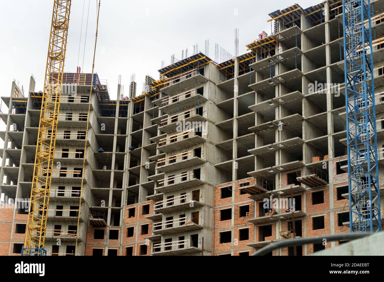 Facciata di un edificio residenziale a più piani in costruzione con una gru di fronte. Foto Stock