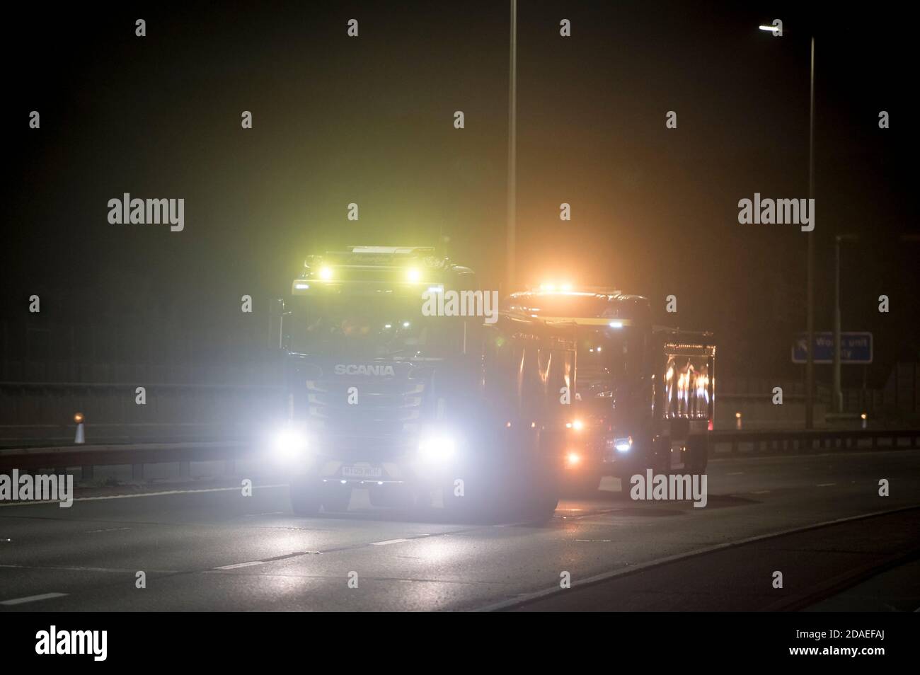 Due camion Scania che guidano vicino insieme sull'autostrada M6 durante la notte, Inghilterra, Regno Unito. Foto Stock