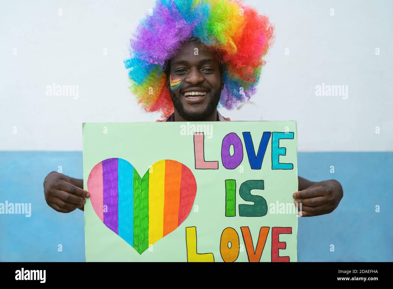 Felice uomo africano che ha divertente tenere bandiera per l'orgoglio gay giorno del festival Foto Stock