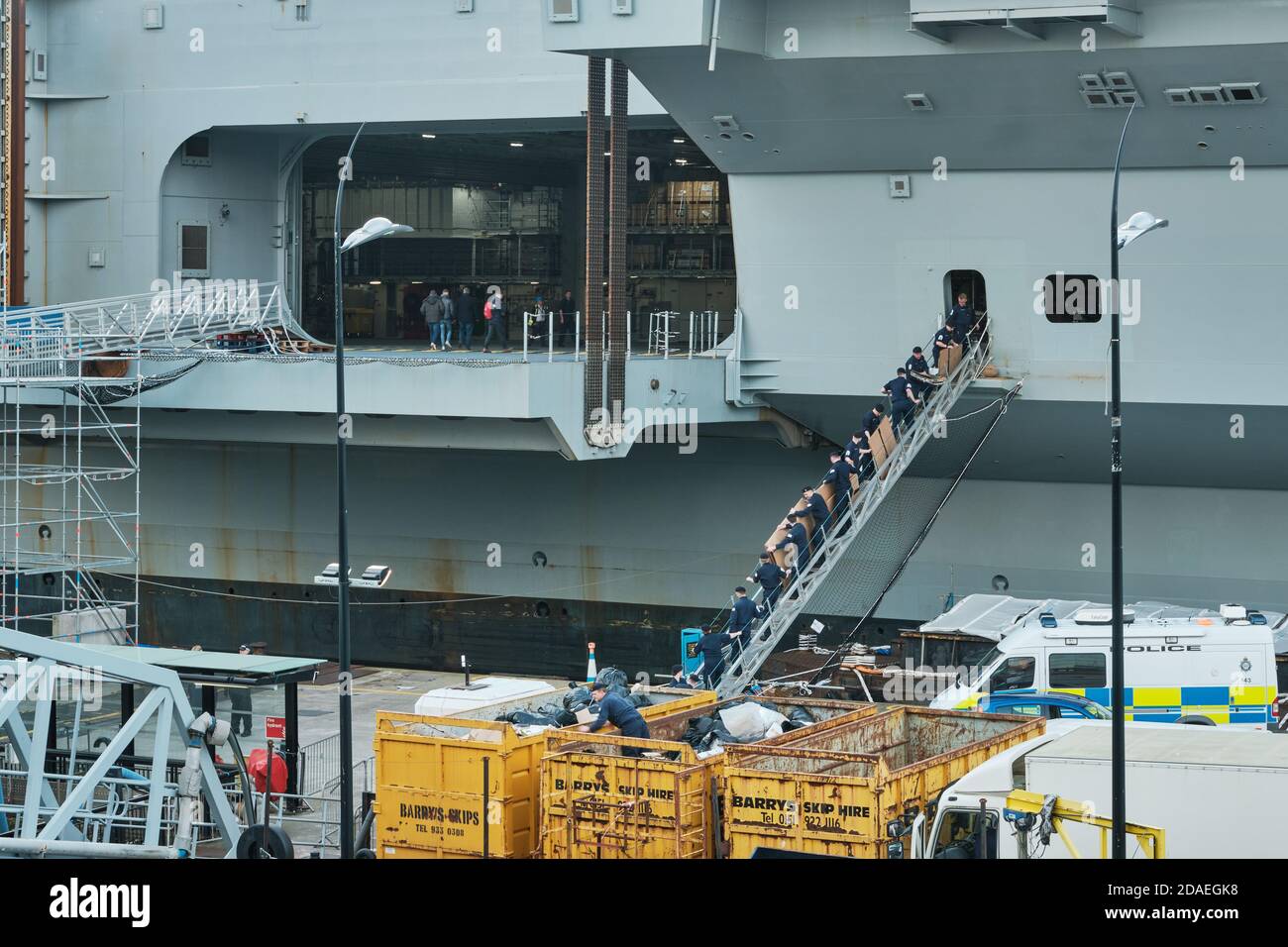 Una catena umana di marinai della Royal Navy svuota i rifiuti dal Principe di Galles HMS in salti. Foto Stock