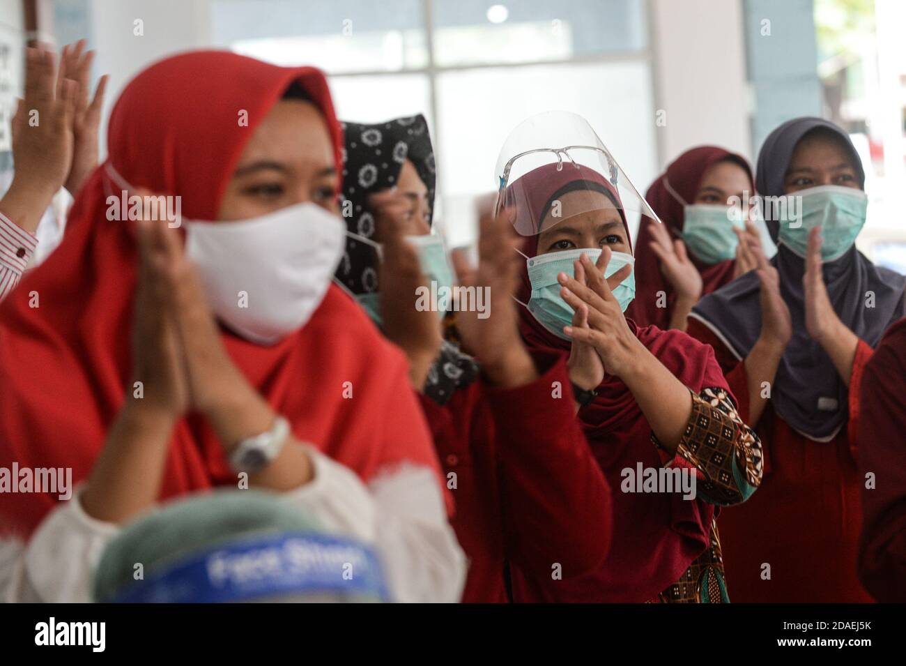 Tangerang meridionale, Indonesia. 12 Nov 2020. Persone che indossano maschere applausi per i medici durante una commemorazione on-line della 56a Giornata Nazionale della Salute presso il centro di salute pubblica di Pondok Betung nel sud Tangerang, Indonesia, 12 novembre 2020. Credit: Agung Kuncahya B./Xinhua/Alamy Live News Foto Stock