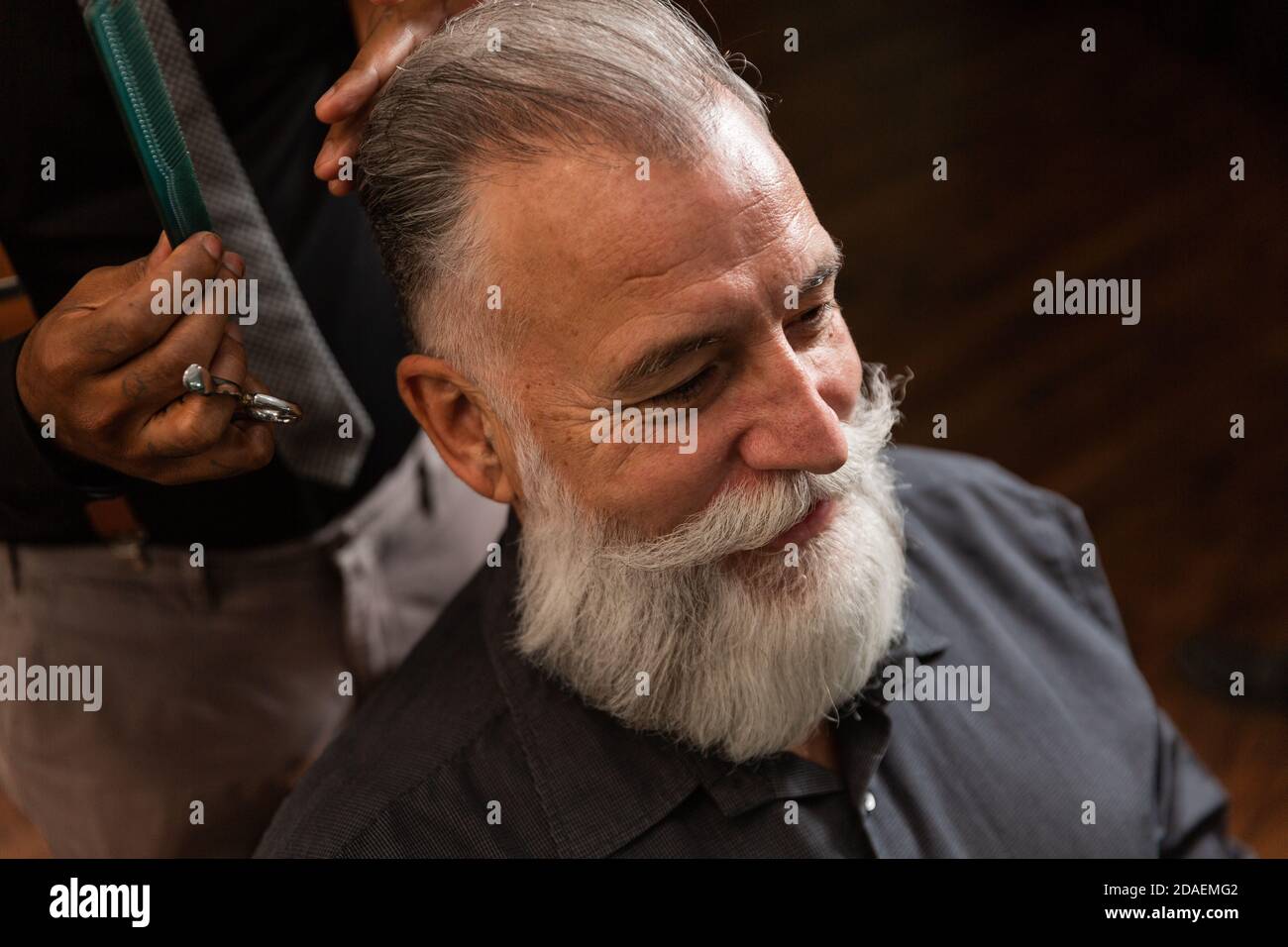 Il barbiere afroamericano rifinisce la barba bianca con la punta a forbice  per i clienti caucasici più anziani Foto stock - Alamy
