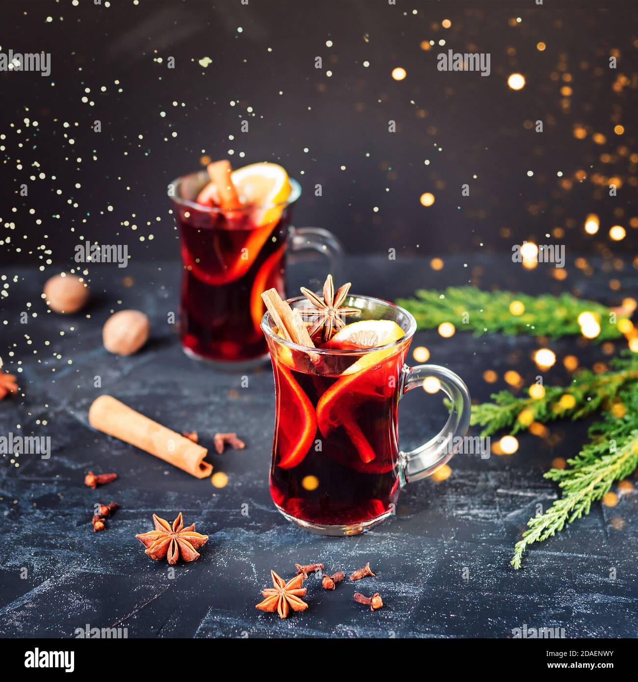 Vino bollito rosso VIN brulé in vetro con arancia, bastoncini di cannella, chiodi di garofano e anice stellato su sfondo nero. Due bevande calde speziate. Tazza di Natale stagionale Foto Stock